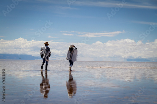 Pareja alegre caminado sobre agua en salar de Uyuni Bolivia.