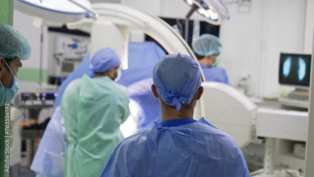 Group of medics in modern surgery room. Doctors producing the C-Arm machine x-ray image of the traumatized body part. Group of medics in modern surgery room. Doctors producing the C-Arm machine x-ray image of the traumatized body part.