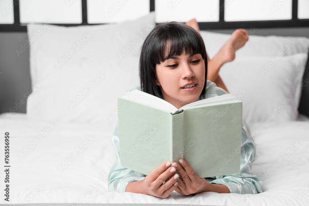 Young woman reading book on bed at home Young woman reading book on bed at home