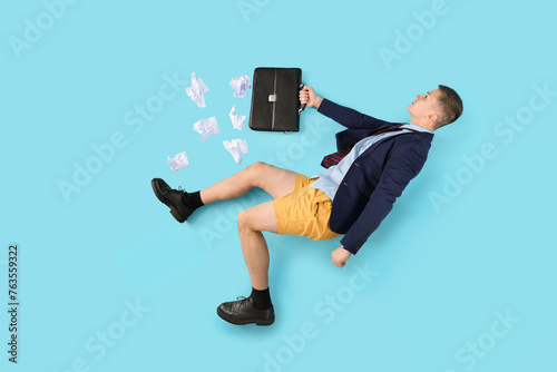 Funny businessman in beach shorts with briefcase and crumpled paper on blue background, top view