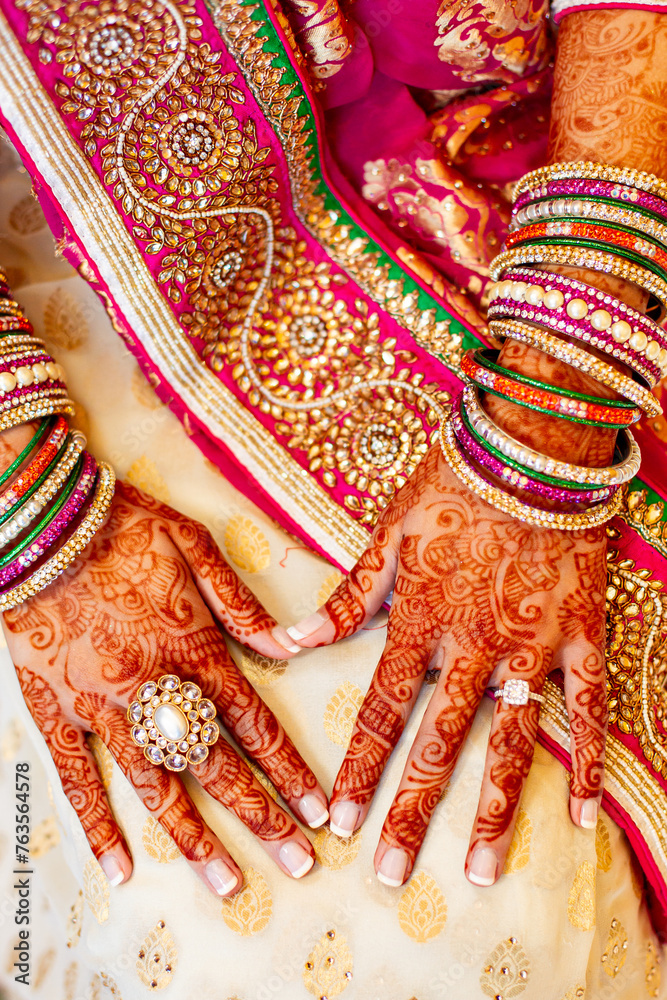 Fototapeta premium Indian bride hands on sari with henna tattoo bangles and diamond wedding ring