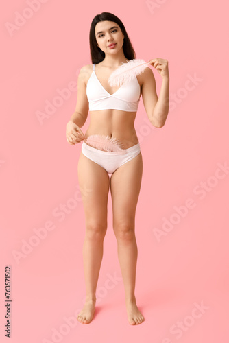 Beautiful young woman with soft feathers on pink background. Epilation concept © Pixel-Shot