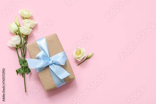 Beautiful wrapped gift box with roses on pink background