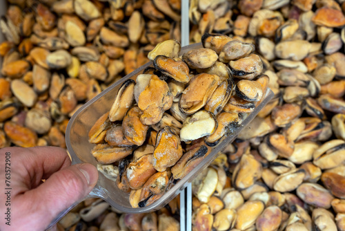 Frozen mussels. Seafood on the counter. Fish market. Close-up shooting of seafood. Photo of mussels in a supermarket. Wholesale of fish. Peeled mussels
