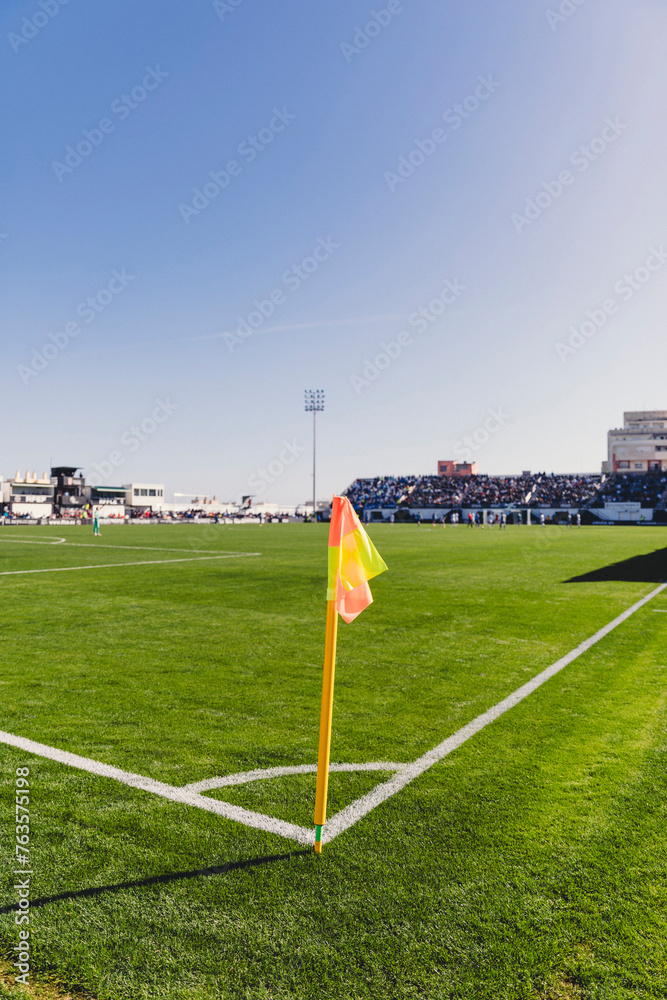 Fototapeta premium Closeup red flag in a football ground corner with bright blue sky