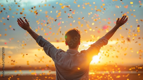 Joyful Person with Arms Raised Celebrating with Confetti at Sunset