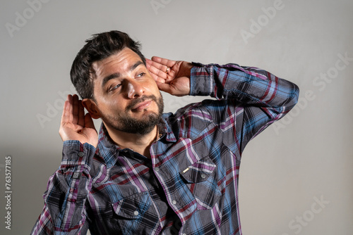 Hombre haciendo gesto de sordera o falta de escucha. Hombre haciendo gesto de Topo Gigio en señal de burla photo