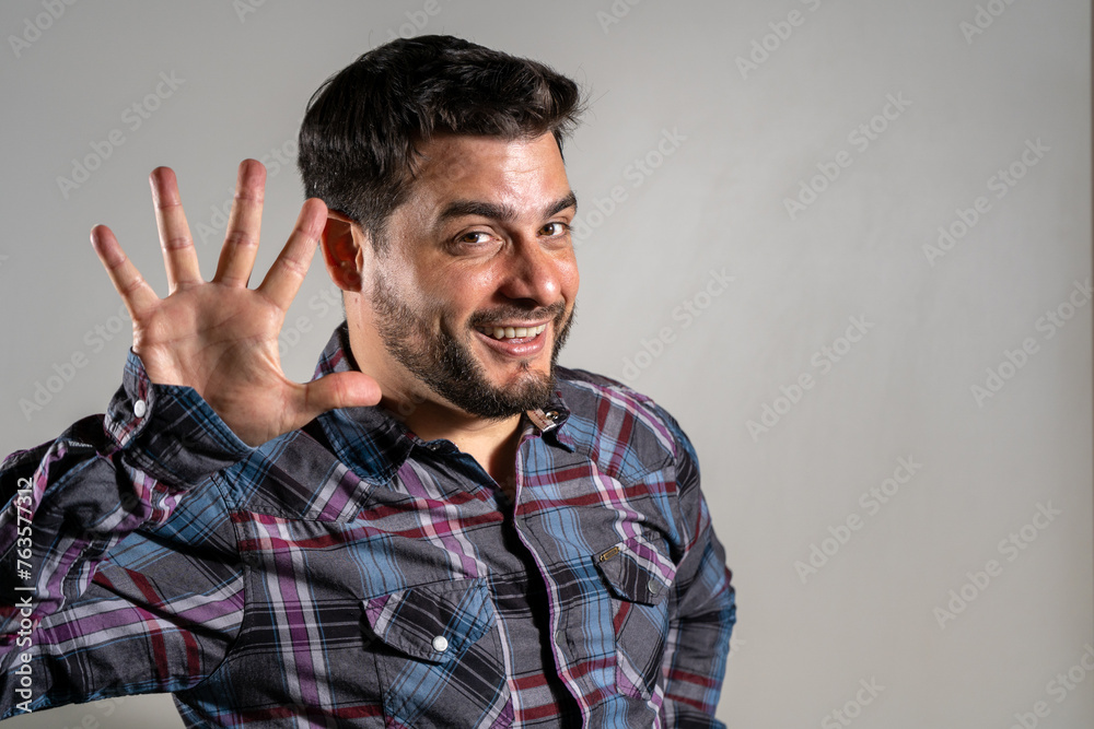 Fototapeta premium Hombre modelo haciendo el numero 5 con la palma de su mano. Hombre saludando. Fotografía de estudio