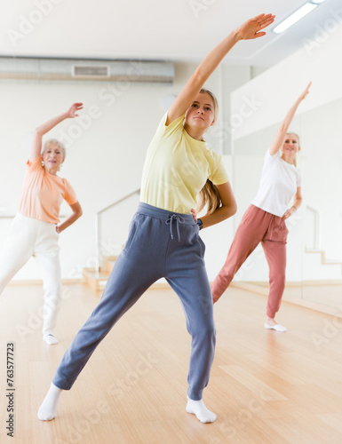 Portrait of cheerful active young girl exercising dance moves in fitness studio