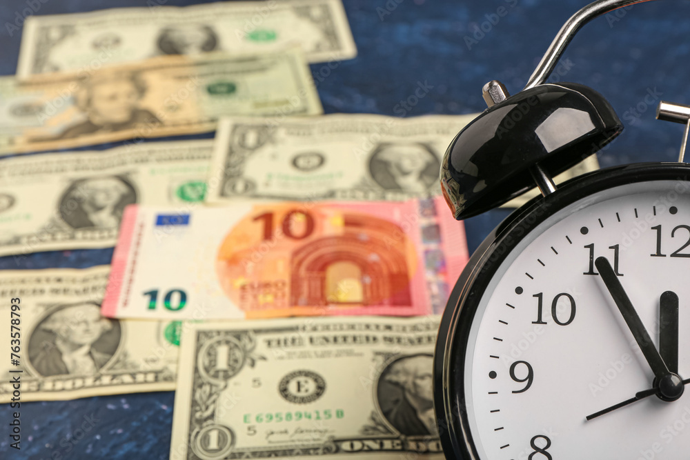 Composition with alarm clock and dollar banknotes on blue grunge background. Time management concept Composition with alarm clock and dollar banknotes on blue grunge background. Time management concept