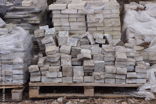 gray paving slabs in a heap on a pallet standing on the ground in the street
