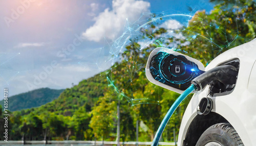 Electric car plug into EV charger cable from charging station display smart digital battery status hologram in eco green park and foliage background. Energy sustainability technological advance.
