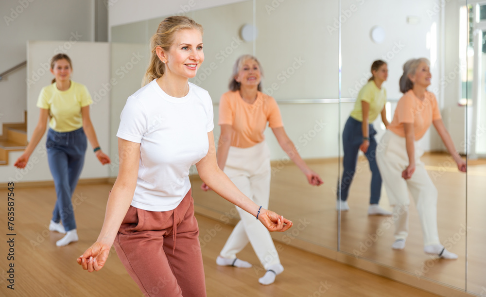 Portrait of positive smiling european woman and people dancing in modern studio