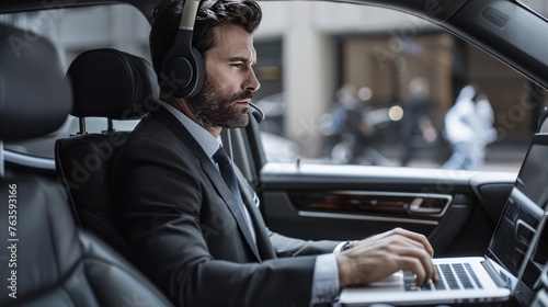 A businessman with Bluetooth headset using laptop in a car with doors opened.