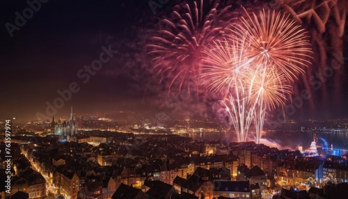 Delicate pink and white fireworks bloom in the night sky above an old city, contrasting with the timeless architecture below. The illuminated streets and buildings add a warm glow to the historic