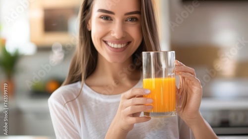 Smiling Young Woman Enjoying Fresh Orange Juice in Kitchen
