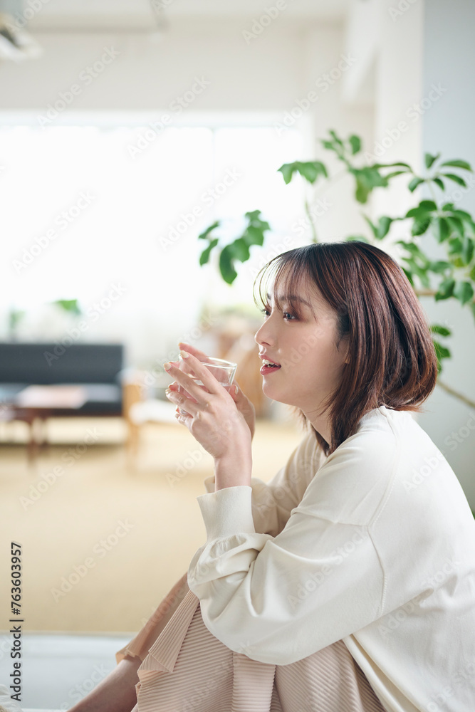 ベッドで水を飲む20代女性