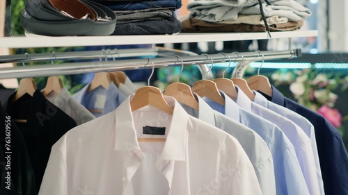 Panning shot of stylish formal clothes on hanger in empty fancy fashion boutique. Latest exquisite designer clothing men shirts collection in premium showroom, close up shot.