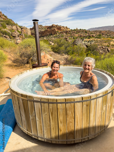 Vleiplaas Clanwilliam Cederberg South Africa. 14/02/2024. Women campers enjoying the wood fired hot tub in the open air. photo