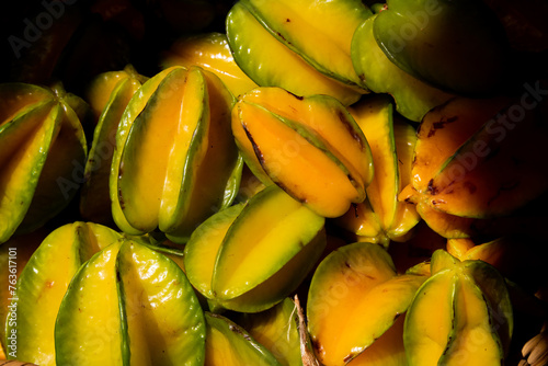Yellow carambola fruits in sunlight against black background