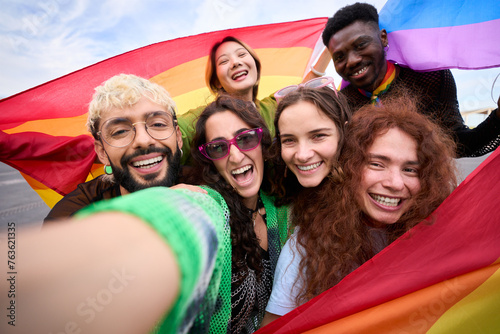 A crowd of happy people in colorful smile for a selfie with a rainbow flag, capturing their fun and leisurely travel recreation. Gay and lesbian friends together in the gay pride parade. LGBT concept