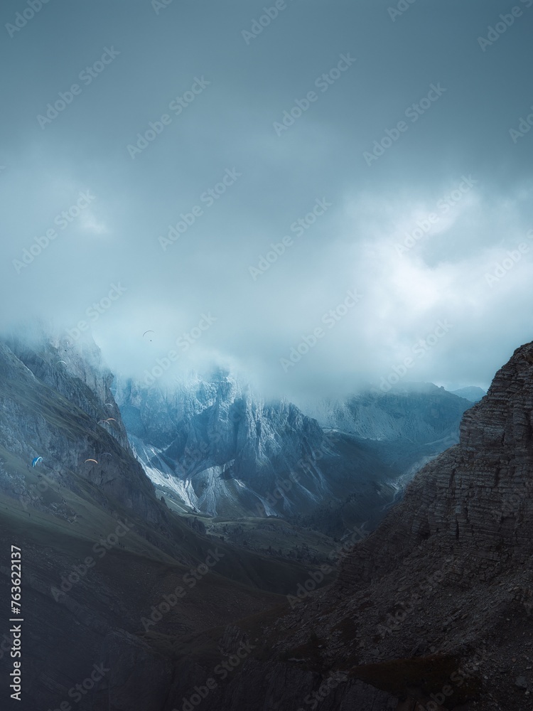 A group of paragliders gliding over the side of Mount Seceda, Dolomites, Italy