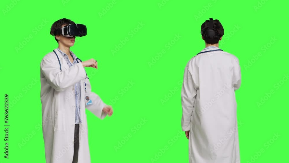 Woman medic works with 3d virtual reality headset in studio, standing against greenscreen backdrop. General practitioner uses vr glasses with interactive vision tool, futuristic exam. Camera B. Woman medic works with 3d virtual reality headset in studio, standing against greenscreen backdrop. General practitioner uses vr glasses with interactive vision tool, futuristic exam. Camera B.