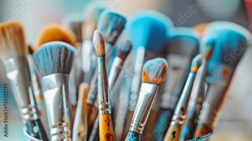 Assorted paint brushes with vivid paint splatters in an artistic studio setting