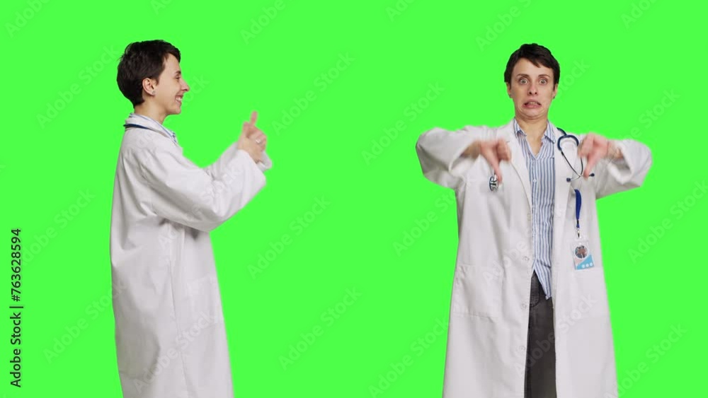 General practitioner showing both like and dislike symbol in studio, expressing approval and disapproval against greenscreen backdrop. Woman medic feels pleased and displeased. Camera B. General practitioner showing both like and dislike symbol in studio, expressing approval and disapproval against greenscreen backdrop. Woman medic feels pleased and displeased. Camera B.