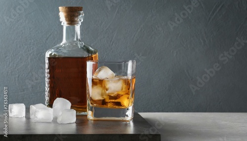 On the Rocks: Whiskey with Ice Cubes in Glass and Bottle on Table, Space for Text photo