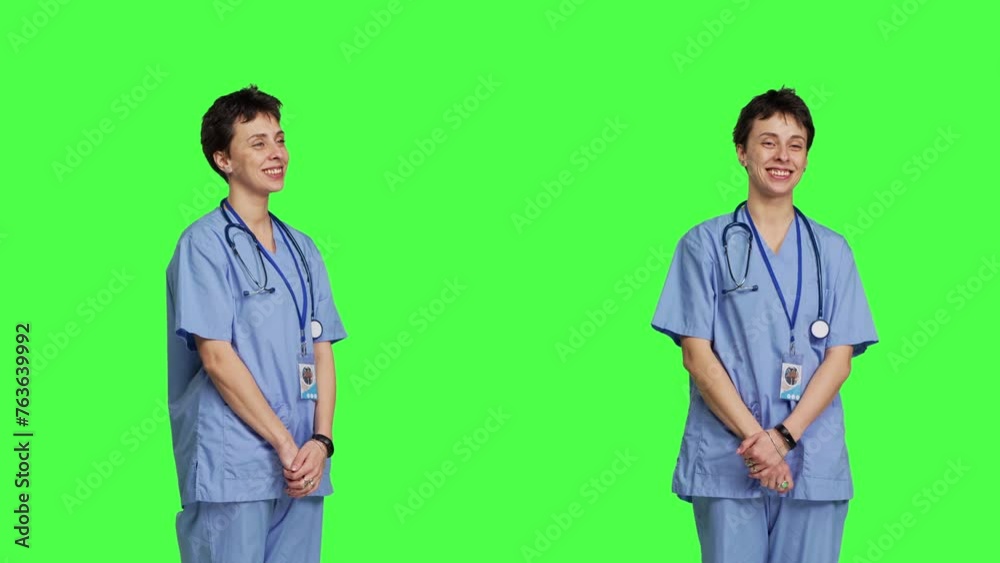 Joyful medical assistant greeting patients with a smile and waving, saying hello in studio against greenscreen backdrop. Smiling cheerful nurse welcoming people at healthcare clinic. Camera B. Joyful medical assistant greeting patients with a smile and waving, saying hello in studio against greenscreen backdrop. Smiling cheerful nurse welcoming people at healthcare clinic. Camera B.