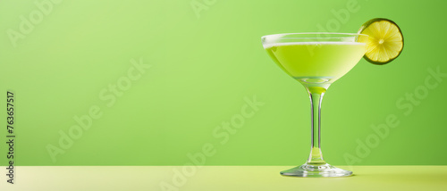 A vibrant green drink served in a stylish margarita glass, garnished with a fresh slice of lime on the rim. Cinco de Mayo theme. Banner. Copy space.