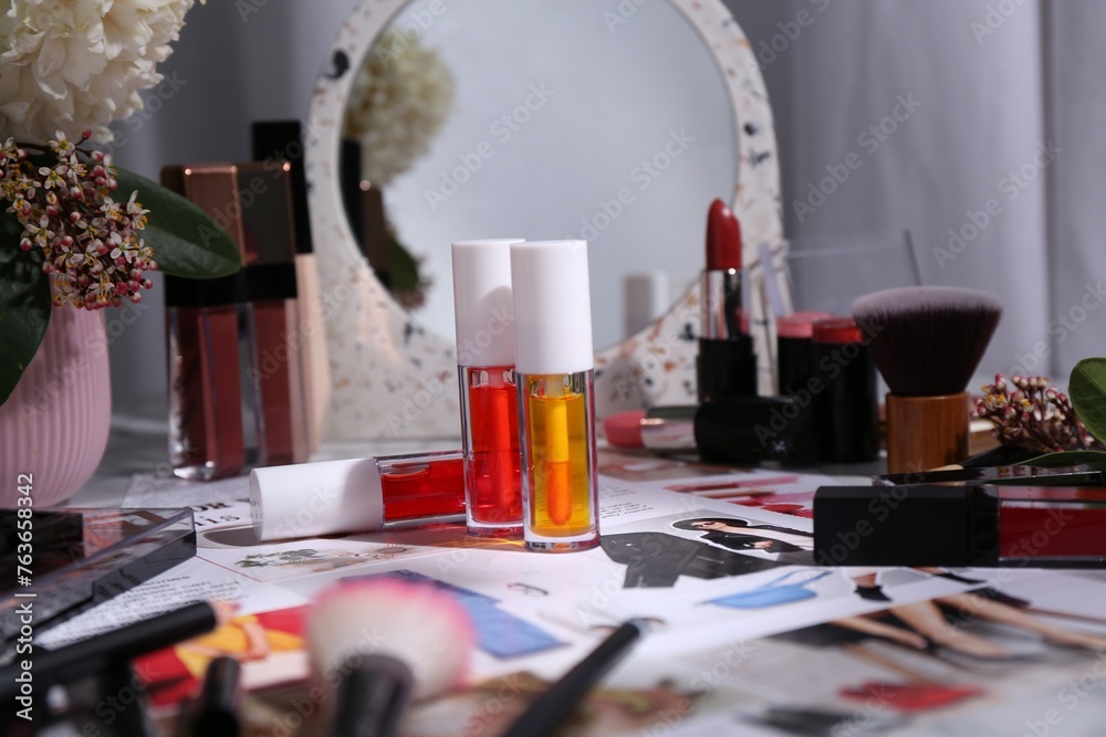 Bright lip glosses among different cosmetic products and fashion magazine on table indoors - obrazy, fototapety, plakaty 