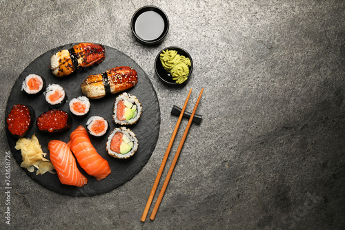 Set of delicious sushi rolls on dark grey table, flat lay