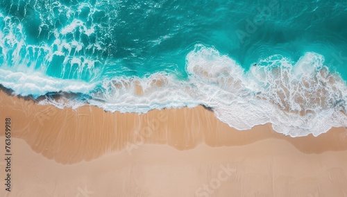 Aerial view of gentle waves on a pristine beach, where turquoise sea meets golden sand.