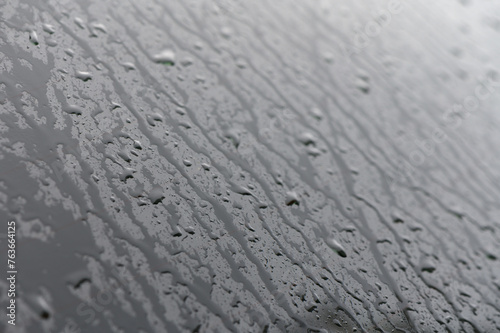 Full frame of the water droplets sliding on a black wet surface.1