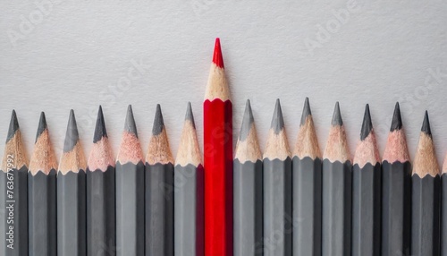 Gray colored pencils, one red colored pencil in one line on white paper background with copy space