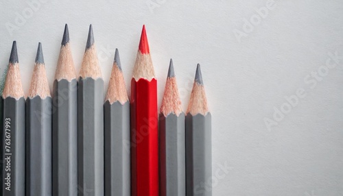 Gray colored pencils, one red colored pencil in one line on white paper background with copy space
