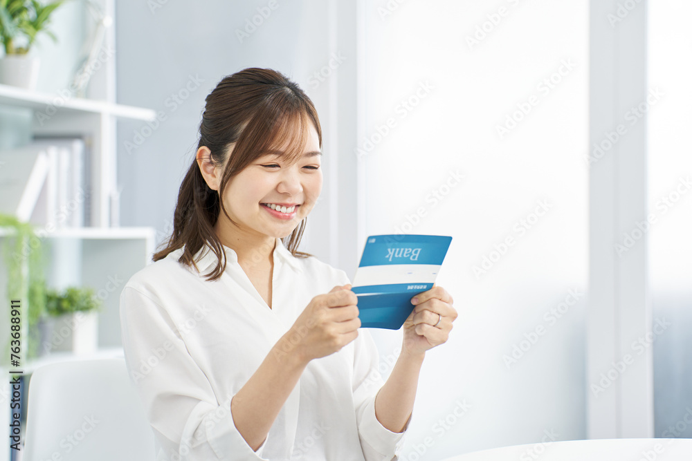笑顔で銀行の通帳を見る女性
