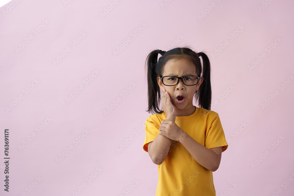 A close-up photo of a cute, cheerful, smart, well-educated little girl with new ideas and imagination. Toothache during childhood copy space and a pink pastel background. A close-up photo of a cute, cheerful, smart, well-educated little girl with new ideas and imagination. Toothache during childhood copy space and a pink pastel background.