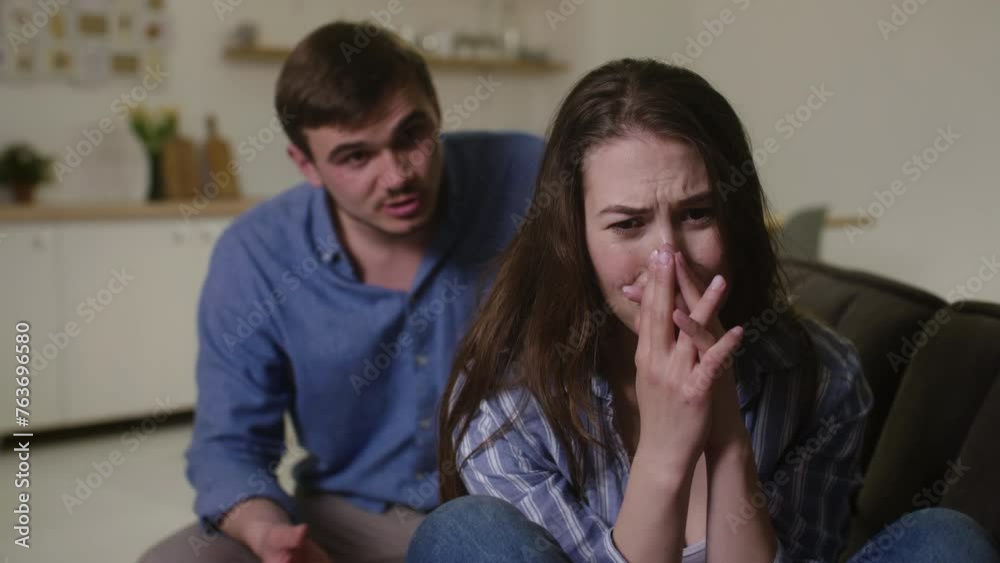Emotional Turmoil: Woman Tearfully Reacts to Man's Accusations of Dishonesty on Home Sofa Emotional Turmoil: Woman Tearfully Reacts to Man's Accusations of Dishonesty on Home Sofa