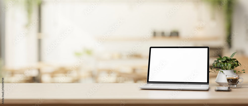 A laptop computer and a presentation space on a wooden table in a cosy, contemporary coffee shop. A laptop computer and a presentation space on a wooden table in a cosy, contemporary coffee shop.