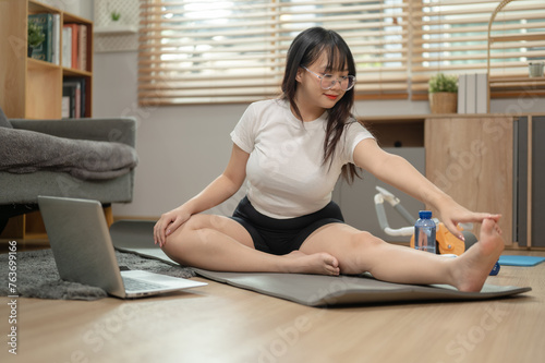 A fit Asian woman in sportswear is doing yoga at home, following the yoga video tutorial online.