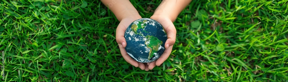 A young child holds a realistic Earth globe on a grass background shaped like a world map A young child holds a realistic Earth globe on a grass background shaped like a world map