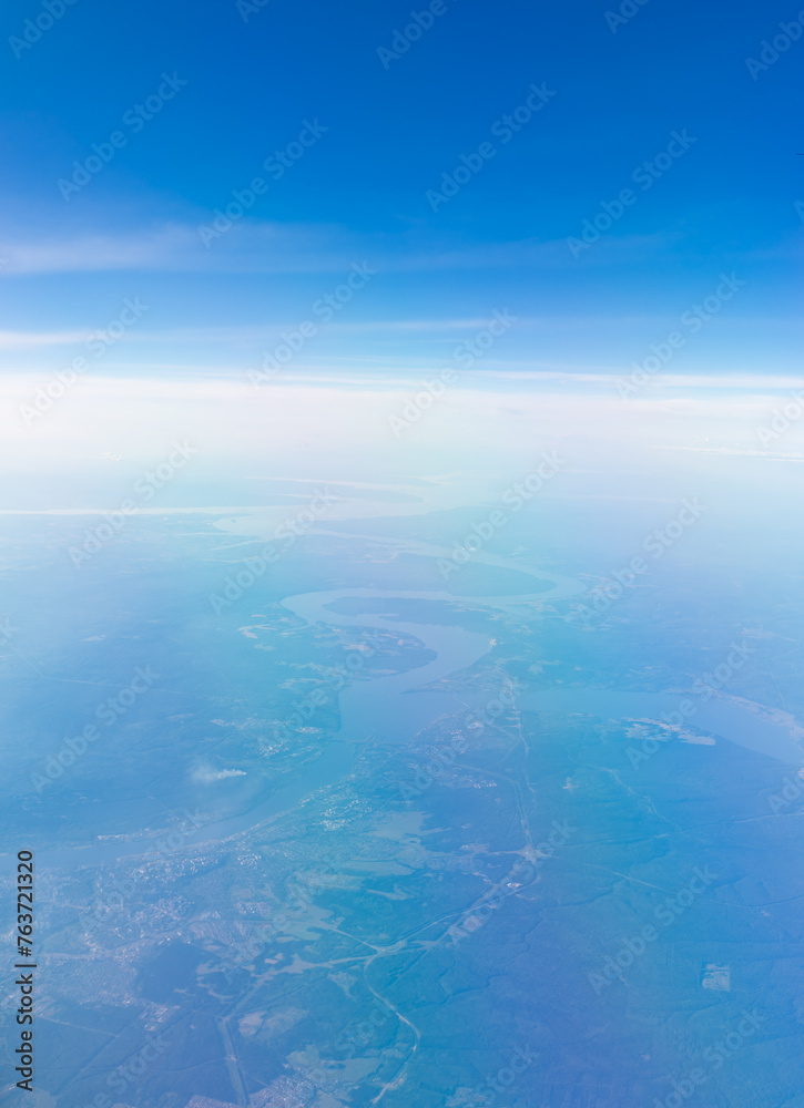 Aerial view from airplane window above green ground. View from the airplane window with beautiful clouds at sunrise Aerial view from airplane window above green ground. View from the airplane window with beautiful clouds at sunrise