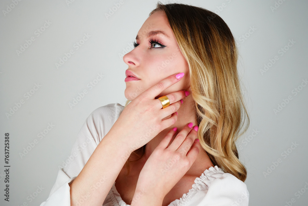 Captivating brunette model showcasing gold ring. Blue-eyed beauty in white shirt against pristine white backdrop. Captivating brunette model showcasing gold ring. Blue-eyed beauty in white shirt against pristine white backdrop.