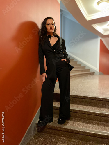 Brunette girl in black pantsuit. The fashion style image is black. The girl on the stairs.
