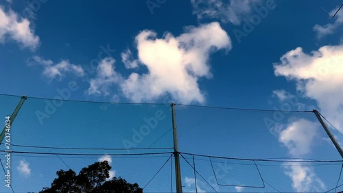 雲が流れる青空とグラウンドのネット