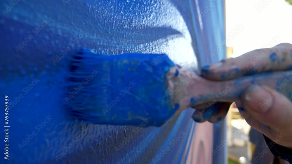 PENNELLO, VERNICE, COLERE BLU 24-0302Pittore dipinge una parete di colore blu. Primo piano sul pennello.
Ripresa al rallemtatore delle setole del pennello su un murals colorato di blu.