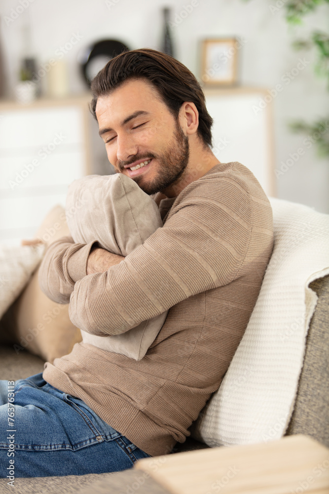 handsome cheerful young man sitting on the couch at home handsome cheerful young man sitting on the couch at home